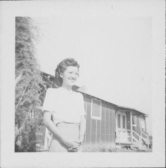 [Young woman wearing eyeglasses standing next to vine in front of barracks, Rohwer, Arkansas, September 23, 1944]