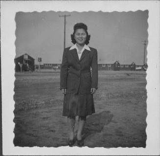 [Young woman in suit standing in open area, full-length portrait, Rohwer, Arkansas]