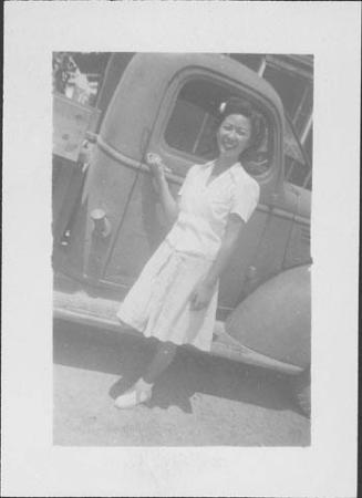 [Young woman with flower in her hair holding onto door handle of truck, Rohwer, Arkansas]