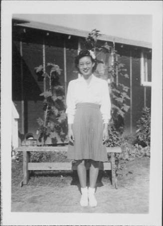 [Young woman in eyeglasses with a flower in hair in front of barracks, Rohwer, Arkansas, October 15, 1944]