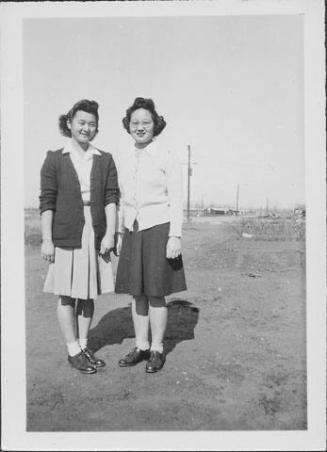[Sisters Misako and Sakaye Nakatsuru standing side-by-side in open area, Rohwer, Arkansas, January 29, 1945]