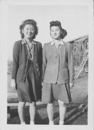 [Misako Nakatsuru and another young women standing side-by-side near barracks, Rohwer, Arkansas, January 29, 1945]