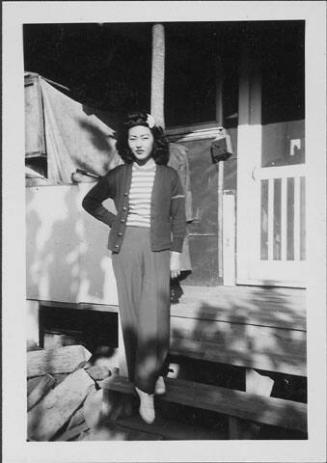 [Young woman in trousers and flower in hair on barracks porch steps, Rohwer, Arkansas, October 16, 1944]