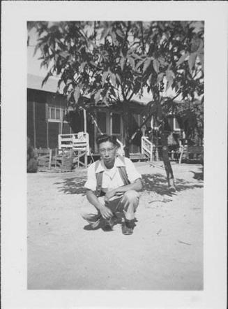 [Young man in vest crouching in front of tree, Rohwer, Arkansas, October 10, 1944]