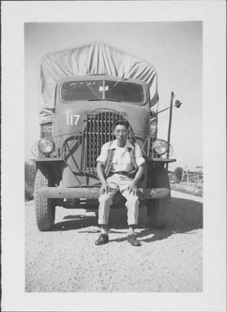 [Young man in vest sitting on front bumper of transport vehicle, Rohwer, Arkansas, October 10, 1944]