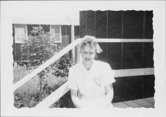 [Young Caucasian woman in nurse's cap sitting on barracks porch steps, Rohwer, Arkansas, July 29, 1944]