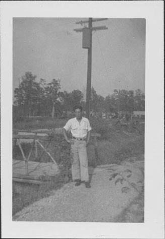 [Man standing next to wooden bridge and utility pole, Rohwer, Arkansas, October 12, 1944]