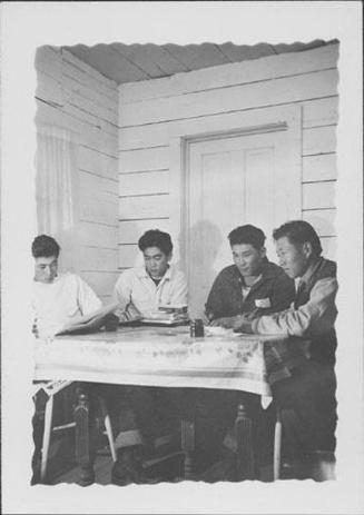 [Four young men seated around table, Rohwer, Arkansas]