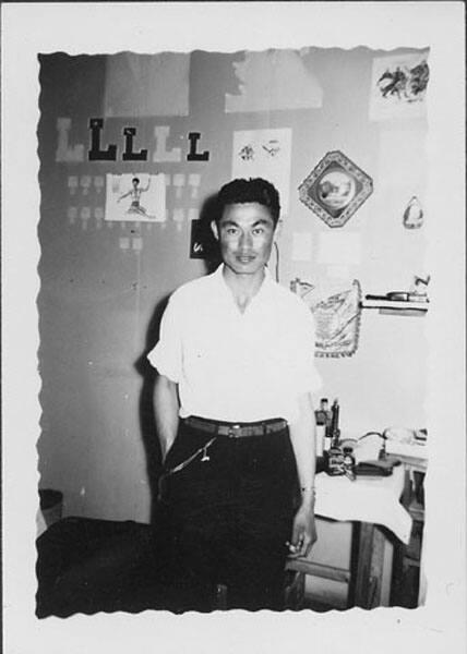 [Man standing in front of wall decorated with "L"s, Rohwer, Arkansas]