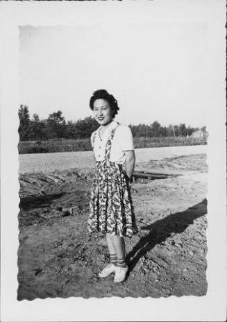 [Young woman in patterned jumper standing in an empty lot, Rohwer, Arkansas]