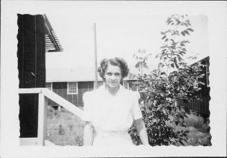 [Caucasian woman outdoors next to barracks railing, half-portrait, Rohwer, Arkansas, July 29, 1944]