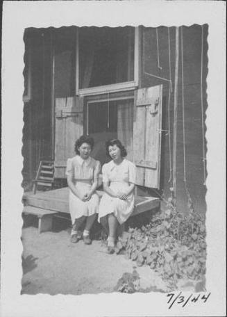 [Two women sitting on deck in front of barracks double-doors, Rohwer, Arkansas, July 3, 1944]