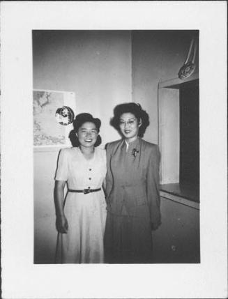 [Two women standing in corner between map and pass-through, Rohwer, Arkansas, June 2, 1945]