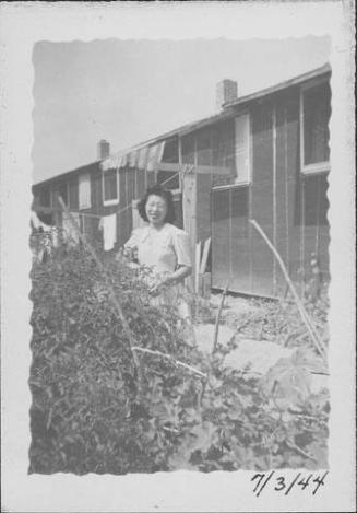 [Woman standing behind shrubs near clothesline, Rohwer, Arkansas, July 3, 1944]