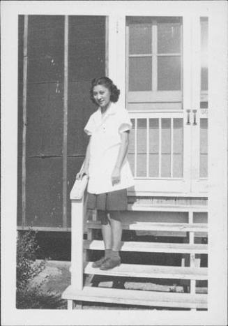 [Young woman in white smock standing on steps, full-length portrait, Rohwer, Arkansas]
