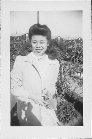 [Woman in white coat holding an envelope in garden, three-quarter portrait, Rohwer, Arkansas, November 25, 1944]