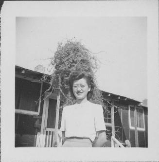 [Woman wearing eyeglasses in front of barracks porch with vine, Rohwer, Arkansas, September 23, 1944]
