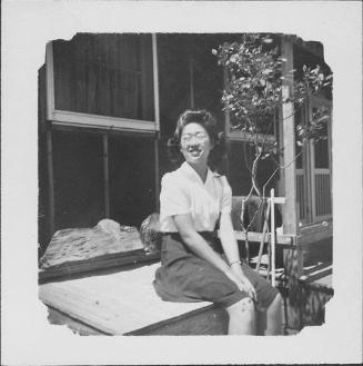[Woman wearing eyeglasses sitting on wooden bin, Rohwer, Arkansas]