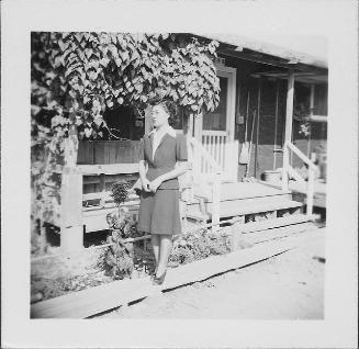 [Woman in suit and eyeglasses posed in front of barracks, 2-7-B, full-length portrait, Rohwer, Arkansas]