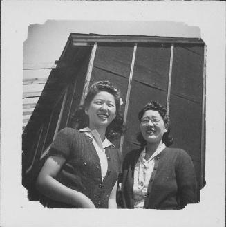 [Two women in sweaters in front of barracks, Rohwer, Arkansas]