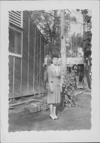 [Young woman in suit near barracks and string trellises, full-length portrait, Rohwer, Arkansas]