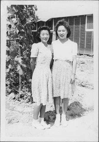 [Two women standing in front of vines and barracks, full-length portrait, Rohwer, Arkansas, July 9, 1944]