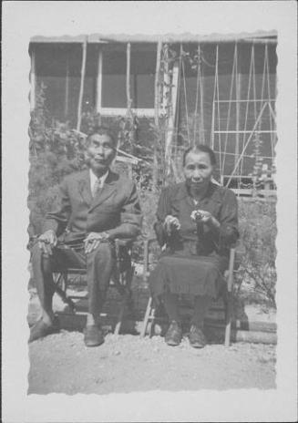 [Older couple holding Buddhist religious articles, seated portrait, Rohwer, Arkansas, July 7, 1944]
