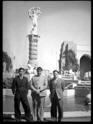 Three men in front of fountain