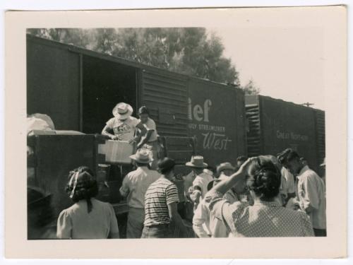 Two men loading train car in front of crowd