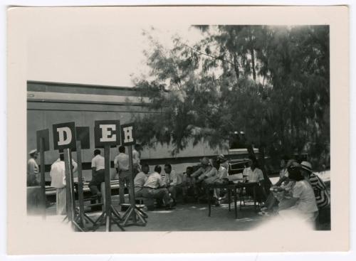 Group waiting at tables with train in background