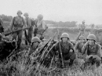 [Soldiers kneeling and standing in field with guns for United States Army Basic training for Korean War, Hawaii, November 1951]
