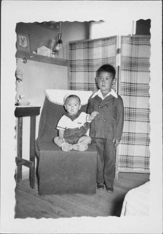[Toddler in sailor outfit sitting on chair next to boy in suit, Rohwer Arkansas, May 24, 1944]