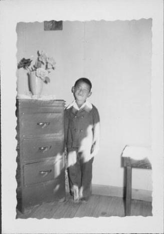 [Smiling boy in suit next to chest of drawers, Rohwer, Arkansas, May 24, 1944]