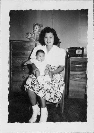 [Woman in floral skirt holding infant in her lap, Rohwer, Arkansas]