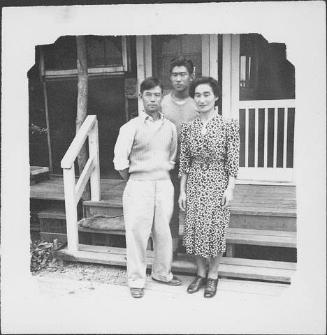 [Three people in front of barracks porch, Rohwer, Arkansas]