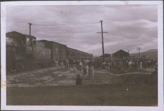 [Large group of people gathered next to a train, Heart Mountain, Wyoming, 1945]
