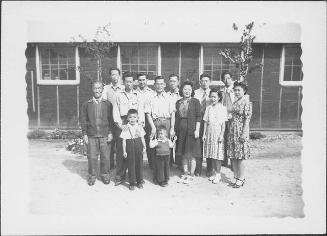 [Group portrait of eleven adults and two boys in front of barracks, Rohwer, Arkansas]
