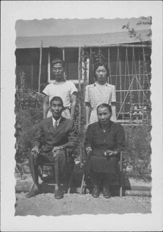 [Seated elderly couple with young man and woman in front of barracks, Rohwer, Arkansas]