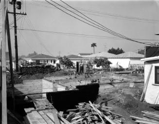 [Mr. Yahata standing on house foundation at construction site, California, March 20, 1955]