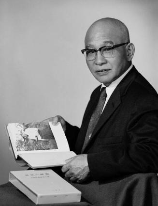 [Mitsuhiko Shimizu of Asahi Shoes and Dry Goods holding book, half-portrait, California, June 2, 1962]