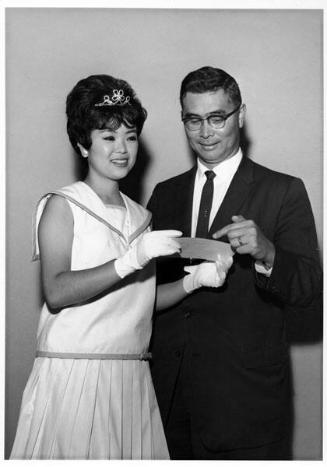 [Nisei Week Princess Betty Taira receives donation from Mr. Omatsu of Downtown JACL at Toyo Miyatake Studio, Los Angeles, California, August 1963]
