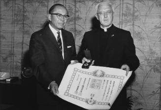 [Father Michael McKillop receiving Fifth Class Order of the Rising Sun award on behalf of Father Hugh T. Lavery at office of Consul General of Japan, Los Angeles, California, June 15, 1966]