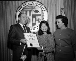 [Los Angeles Mayor Sam Yorty presenting "Girl's Week" proclamation to a young Japanese American woman at City Hall, Los Angeles, California, 1966]