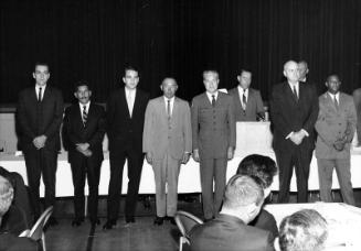 [Men of different ethnicities standing in front of curtained stage, California, 1966?]