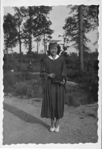 [Young woman in eyeglasses and graduation gown holding diploma, Rohwer, Arkansas, 1942-1945]