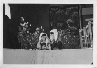 [Blind musican and companion sitting in front of flowers in Kabuki play, Rohwer, Arakansas, Novermber 12, 1944]